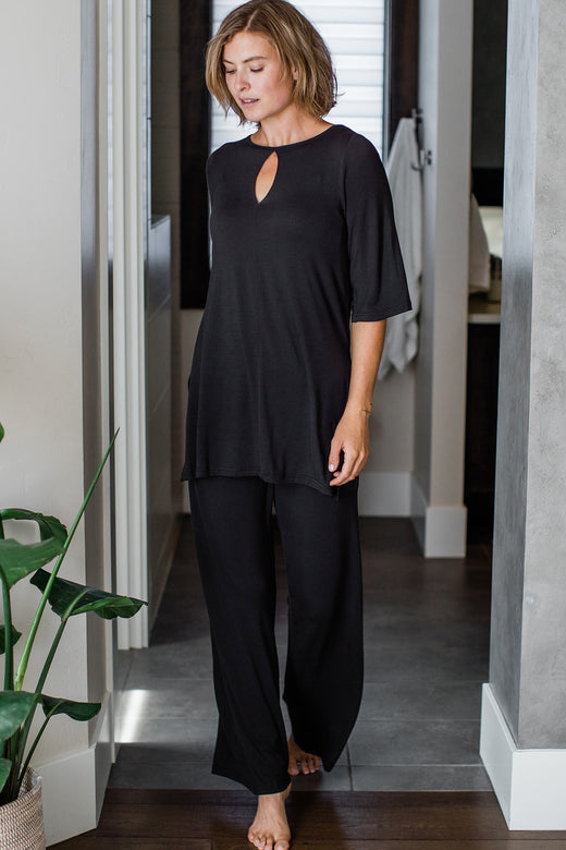 A woman walking forward and looking downward, wearing Yala Kat Lounge Bamboo Pajama Set in Black