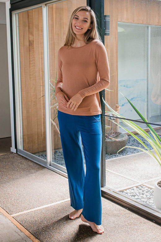 A woman standing and smiling with both hands in front of her waist, wearing Yala Kayla Wide Leg Foldover Waist Bamboo Pants in Lapis
