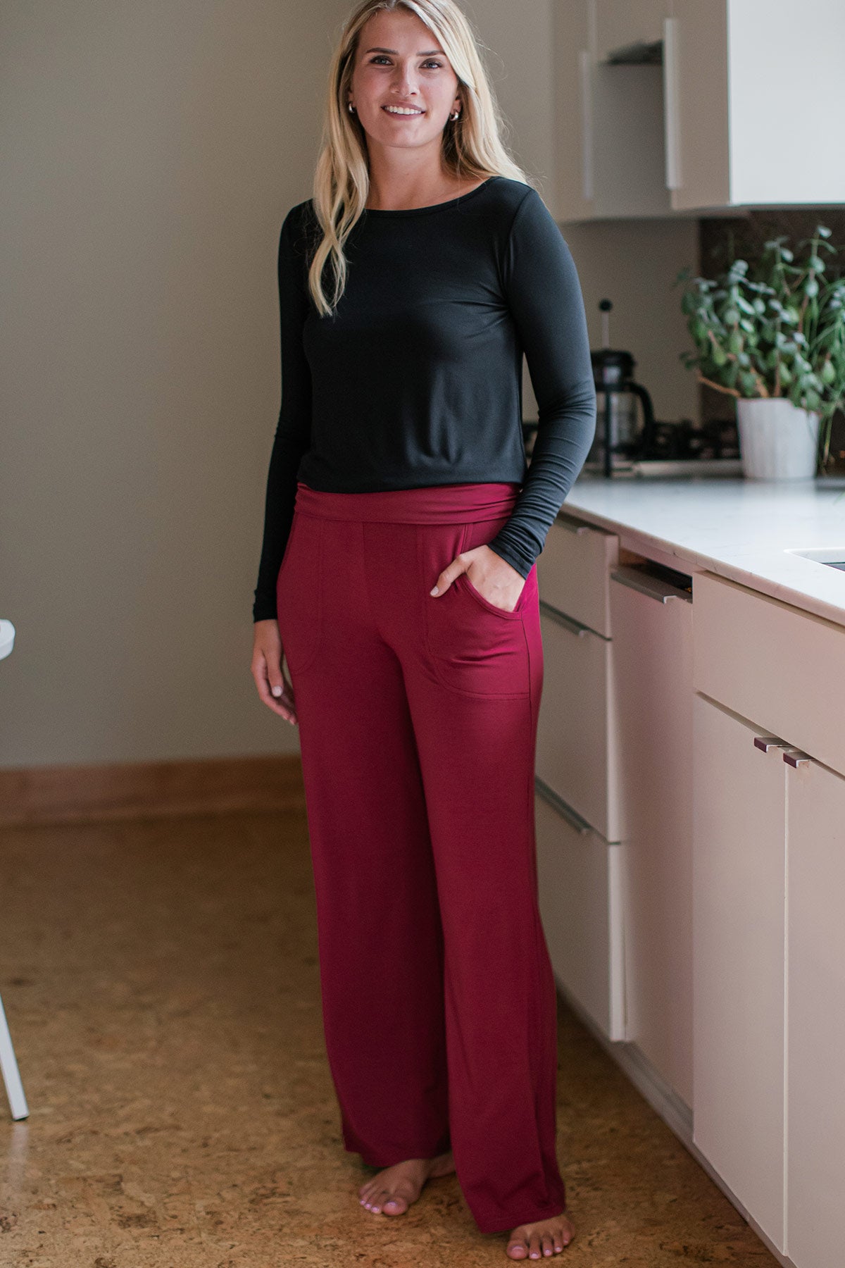 A woman standing and smiling with one hand in her pocket, wearing Yala Kayla Wide Leg Foldover Waist Bamboo Pants in Rosewood