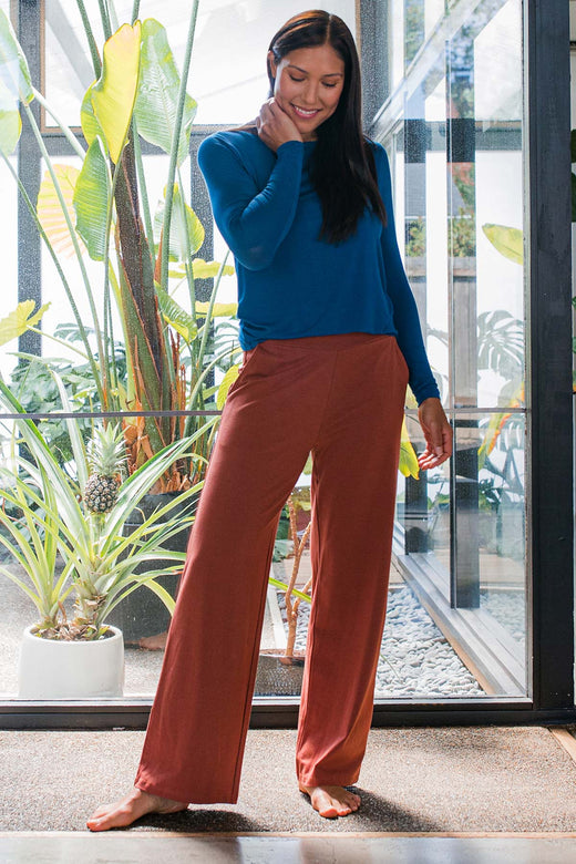 A woman standing with her hand on her neck, looking at the ground, wearing Yala Lexi Ultra-Stretch Bamboo and Organic Cotton Classing Wide Leg Pants in Amber
