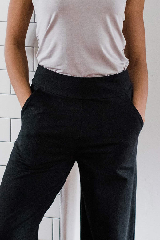 Close shot of a woman's torso and legs, wearing Yala Lexi Ultra-Stretch Bamboo and Organic Cotton Classic Wide Leg Pants in Black