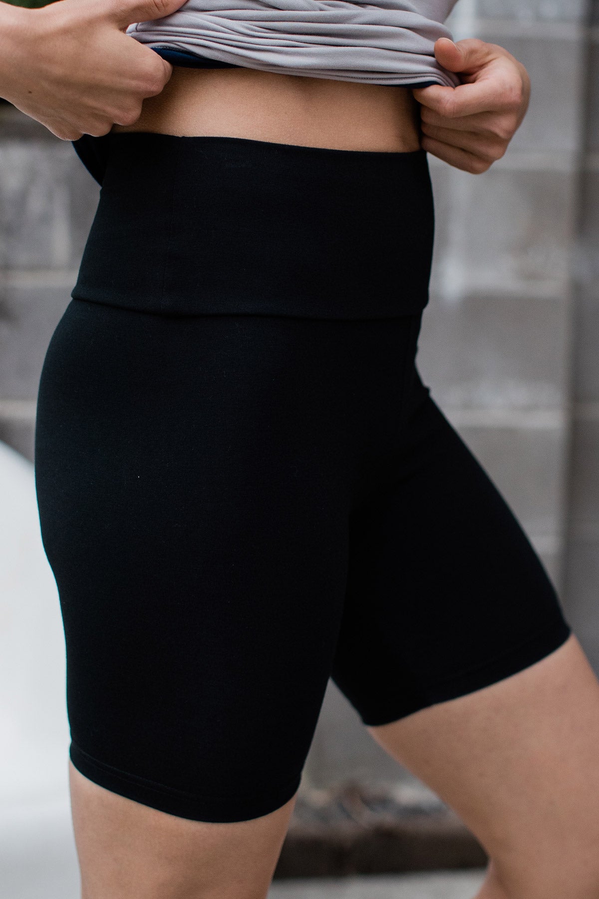 Close shot of a woman's waist and thighs, wearing Yala London Ultra-Stretch High-Waisted Bamboo and Organic Cotton Yoga Shorts in Black