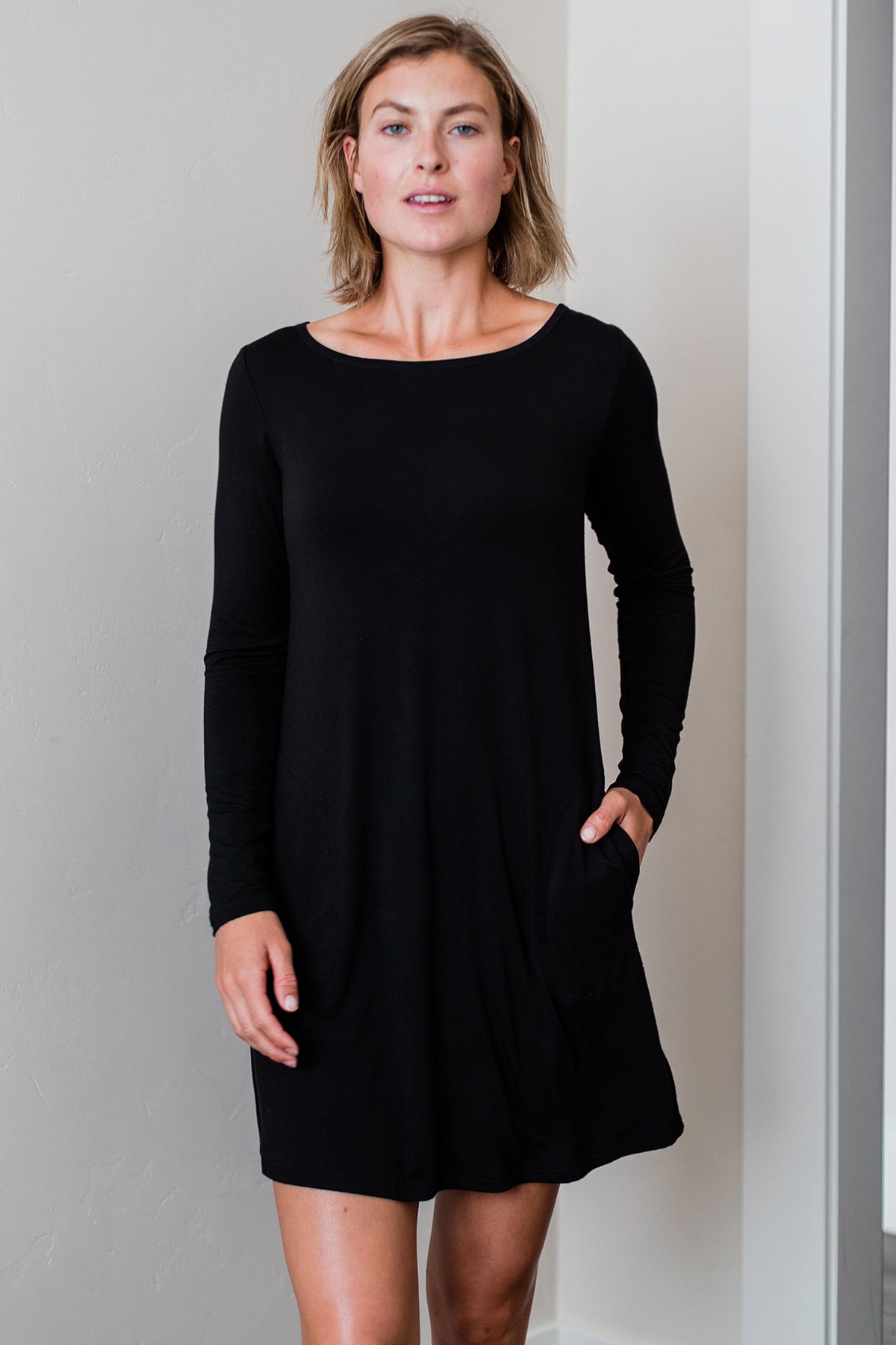 A woman standing with one hand in her pocket, wearing Yala Mia A-Line Bamboo Dress in Black