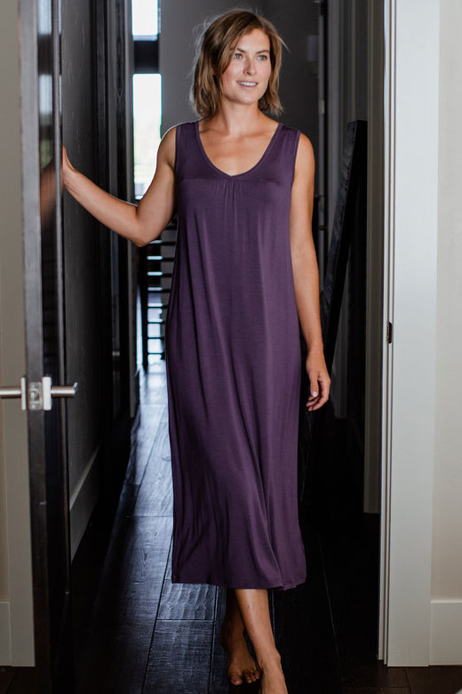 A woman standing with one foot forward and one hand resting on a nearby door, wearing Yala Molly Sleeveless Bamboo Nightgown in Aster