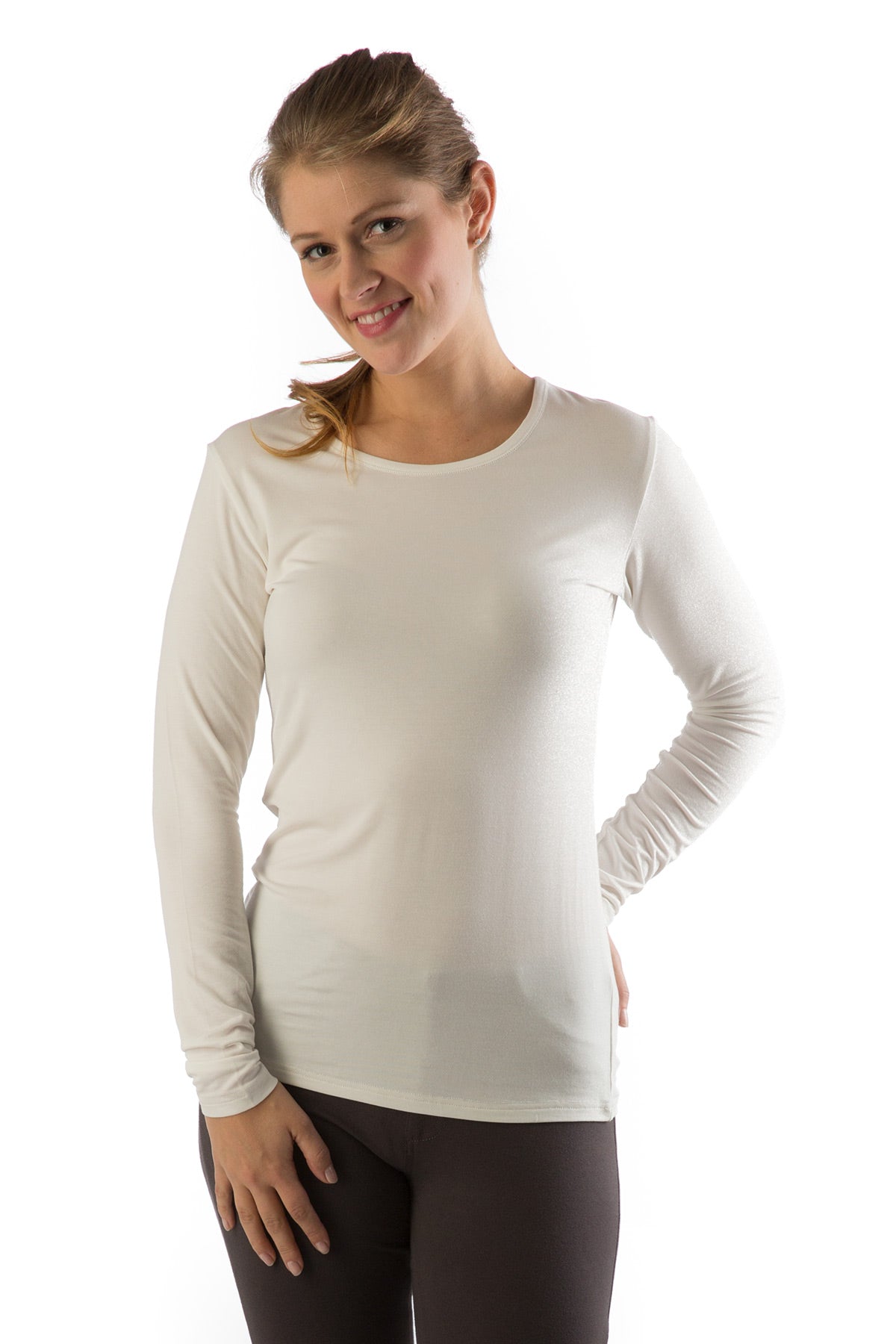 A woman standing and smiling with one hand on her thigh and the other behind her, wearing Yala Natalie Long Sleeve Bamboo Crew Tee Shirt