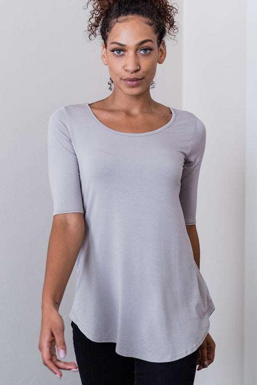 A woman walking forward with one had in front of her, wearing Yala Sandy Relaxed Fit Scoop Neck Short Sleeve Bamboo Top in Ash