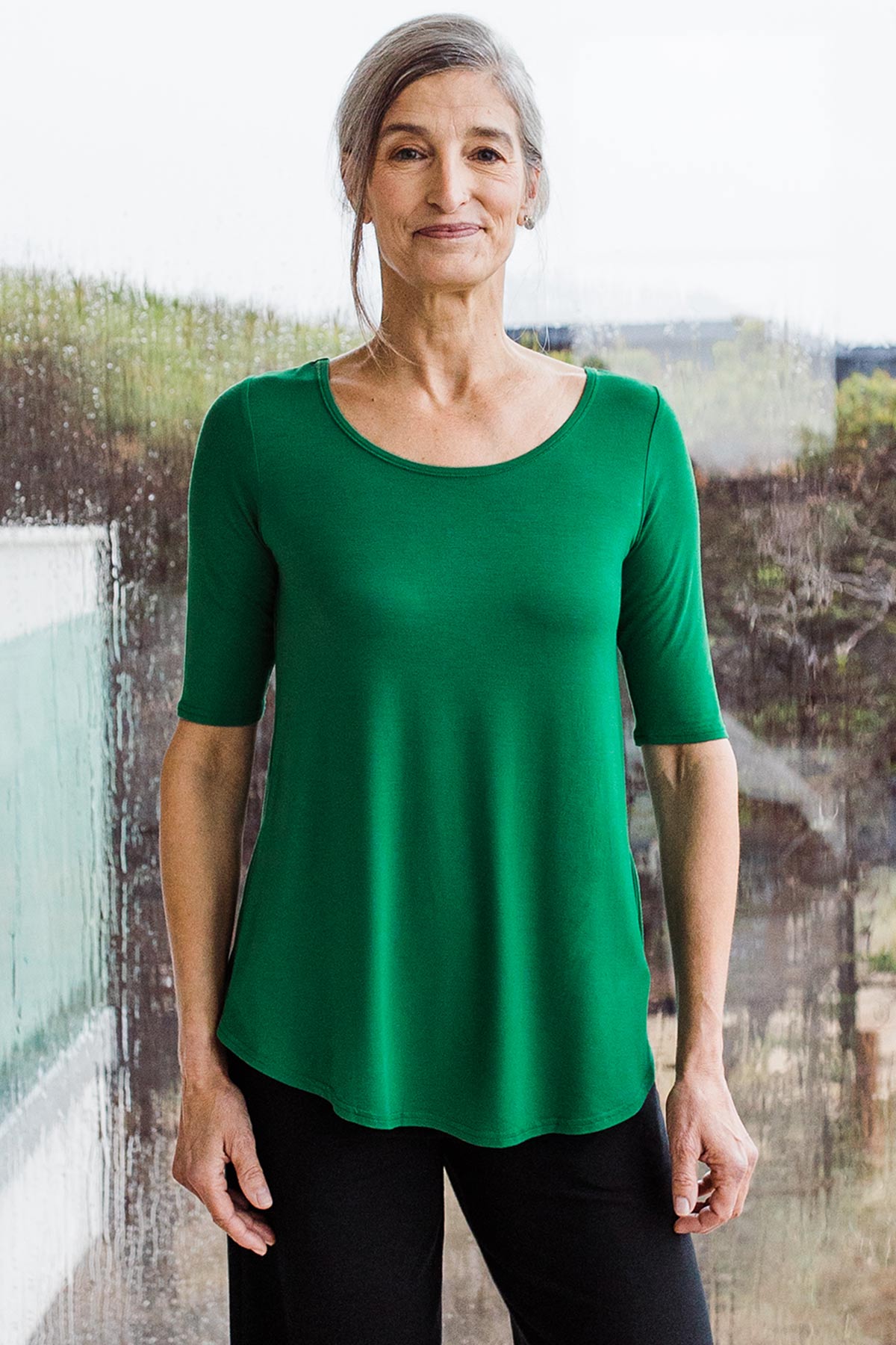 Woman standing in front of a window, wearing Yala Sandy Relaxed Fit Scoop Neck Short Sleeve Bamboo Top
