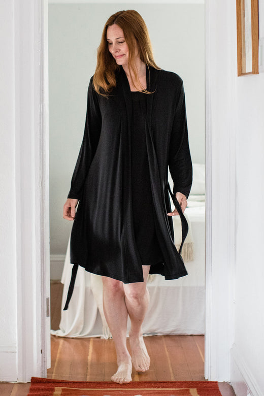A woman walking forward and looking to the side, wearing Yala Serenity Long Sleeve Short Belted Bamboo Robe in Black