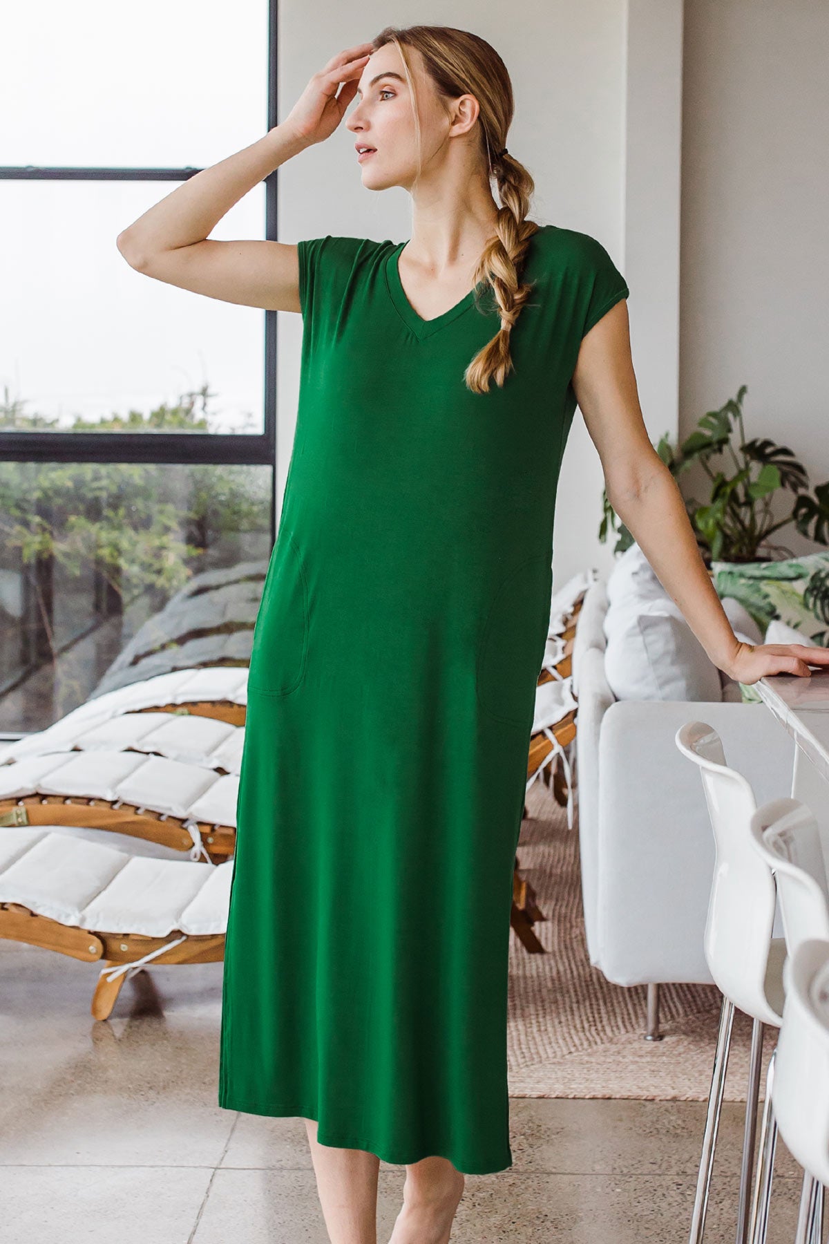 Woman standing and looking to the side with one hand raised to her forehead, wearing Yala Sloane V-Neck Cap Sleeve Bamboo Maxi Dress