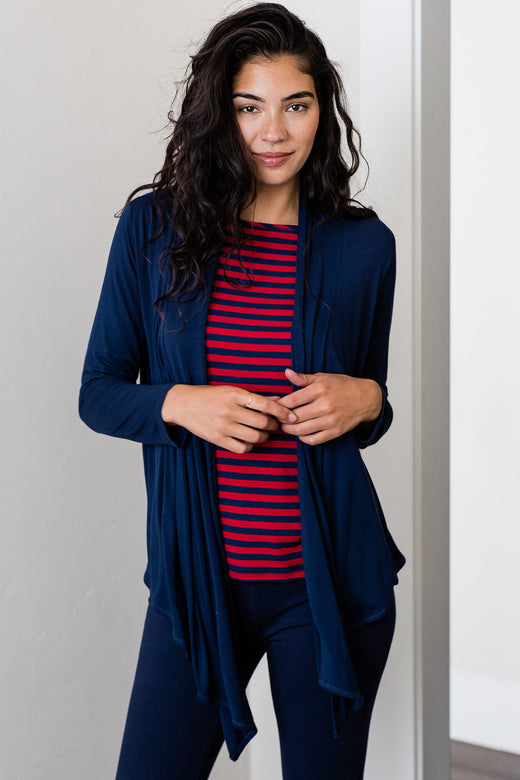 A woman standing with both ands held in front of her chest, wearing Yala Sophie Bamboo Cardigan Wrap in Navy