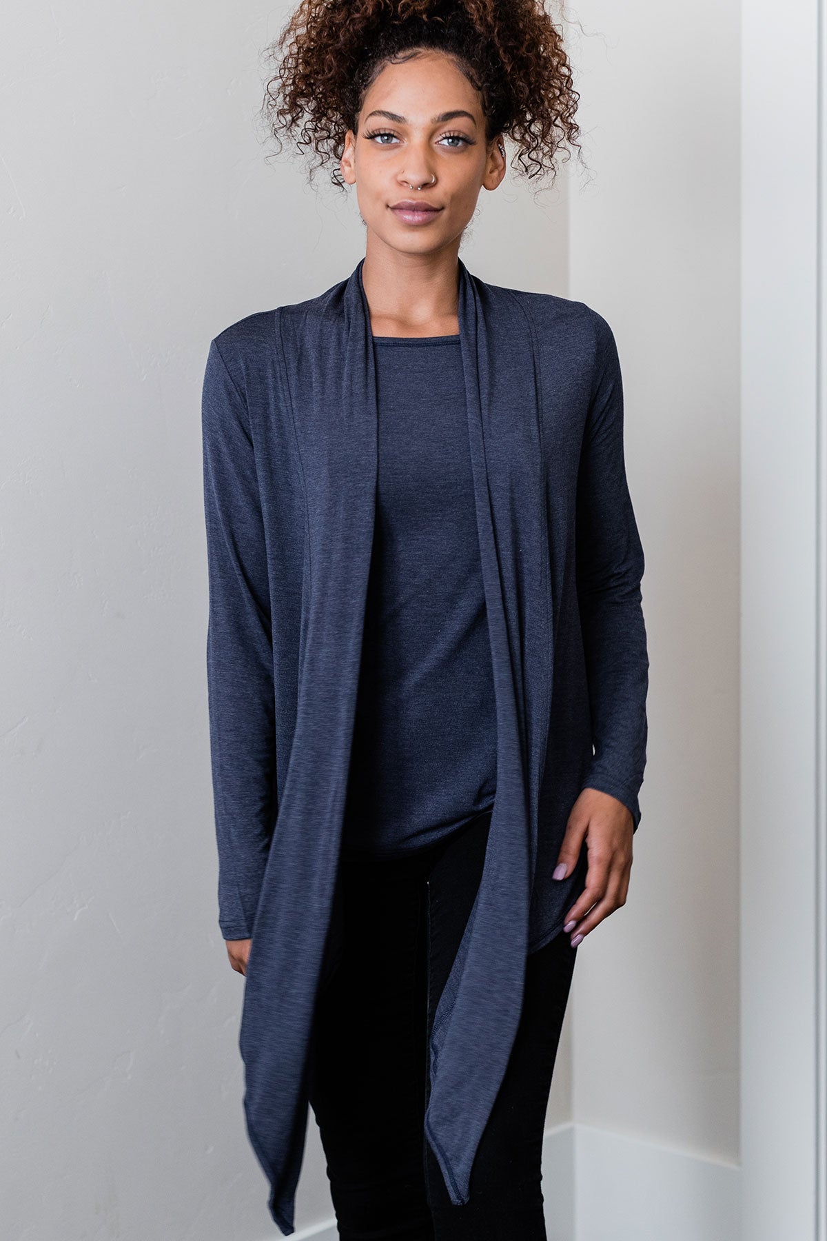 A woman standing with both ahnds at her sides, wearing Yala Sophie Bamboo Cardigan Wrap in Navy Melange
