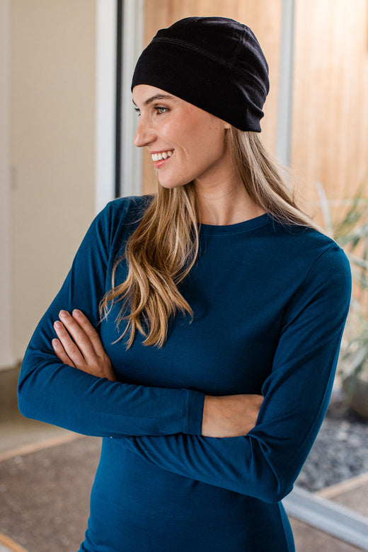 Close shot of a woman with arms crossed, looking to the side and wearing Yala Superfine Merino Wool Beanie Hat in Black