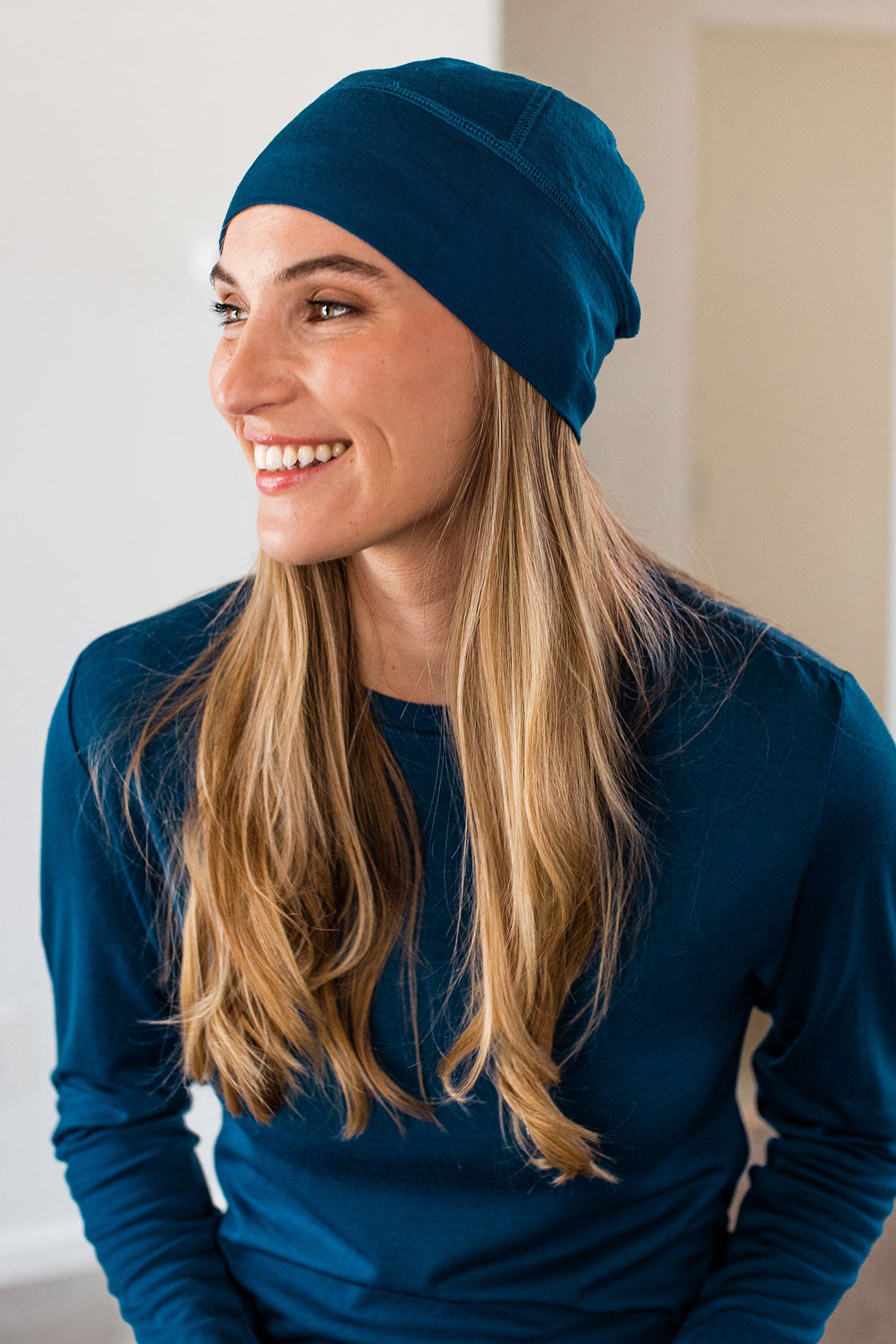 Close shot of a woman smiling and looking to the side, wearing Yala Superfine Merino Wool Beanie Hat in Lapis