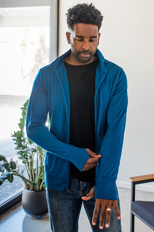A man standing and looking down as he adjusts his sleeve, wearing Yala Superfine Merino Wool Track Jacket in Lapis