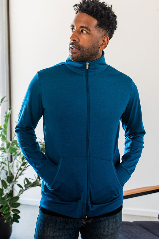 A man standing and looking upward and to the side, hands in his jacket pockets, wearing Yala Superfine Merino Wool Track Jacket in Lapis