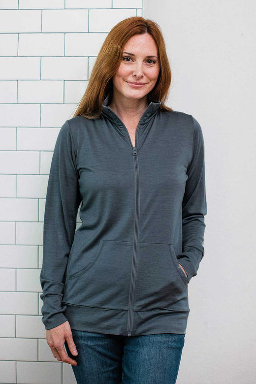 A woman standing and smiling with one hand in her jacket pocket, wearing Yala Superfine Merino Wool Track Jacket in Storm Grey