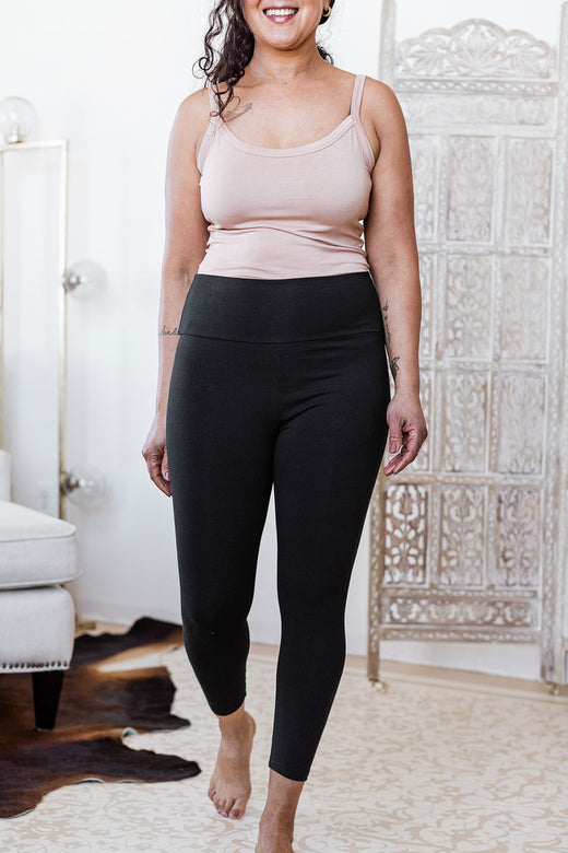 A woman walking forward and smiling with both hands at her sides, wearing Yala Sydney Ultra-Stretch High-Waisted Bamboo and Organic Cotton Cropped Leggings in Black
