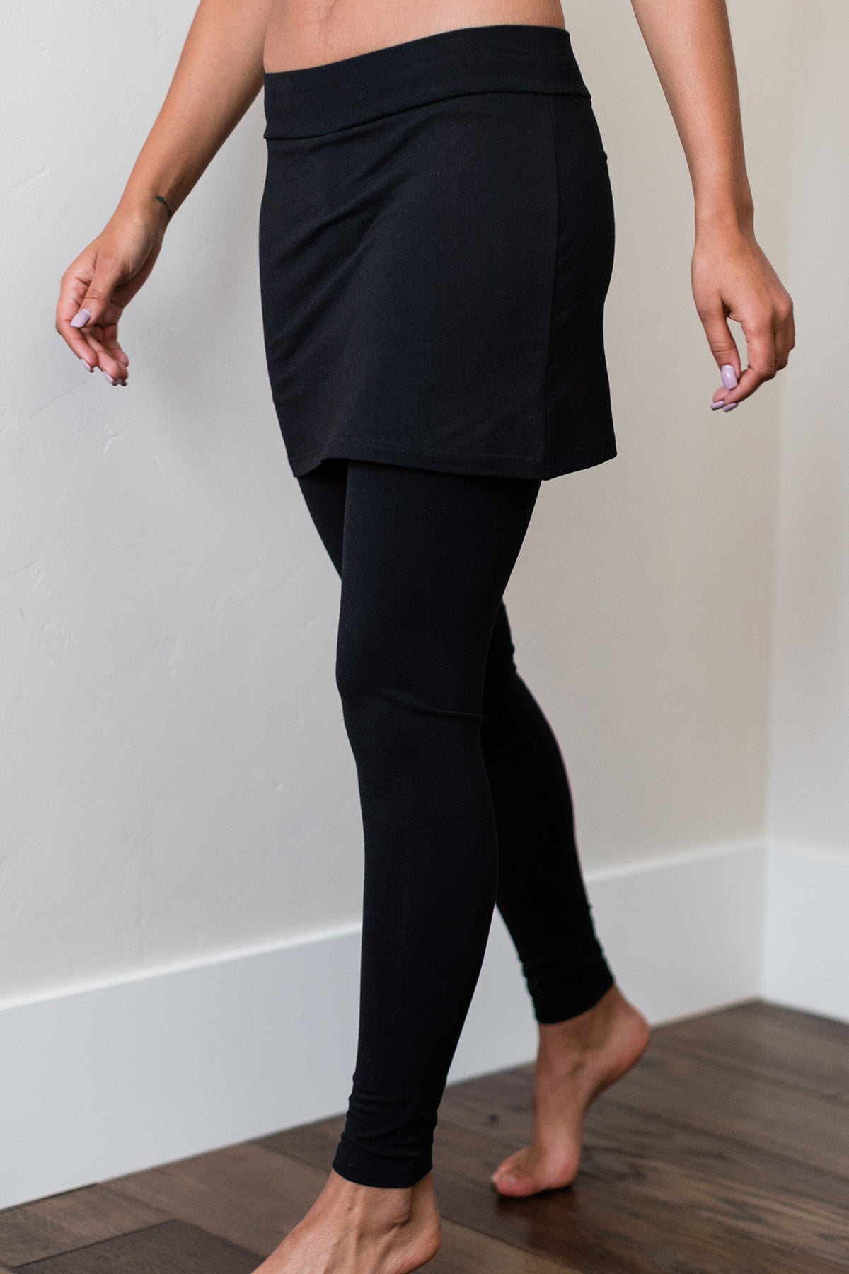 Close shot of a woman's hips and legs, wearing Yala Taylor Ultra-Stretch Bamboo and Organic Cotton Skirt Leggings in Black