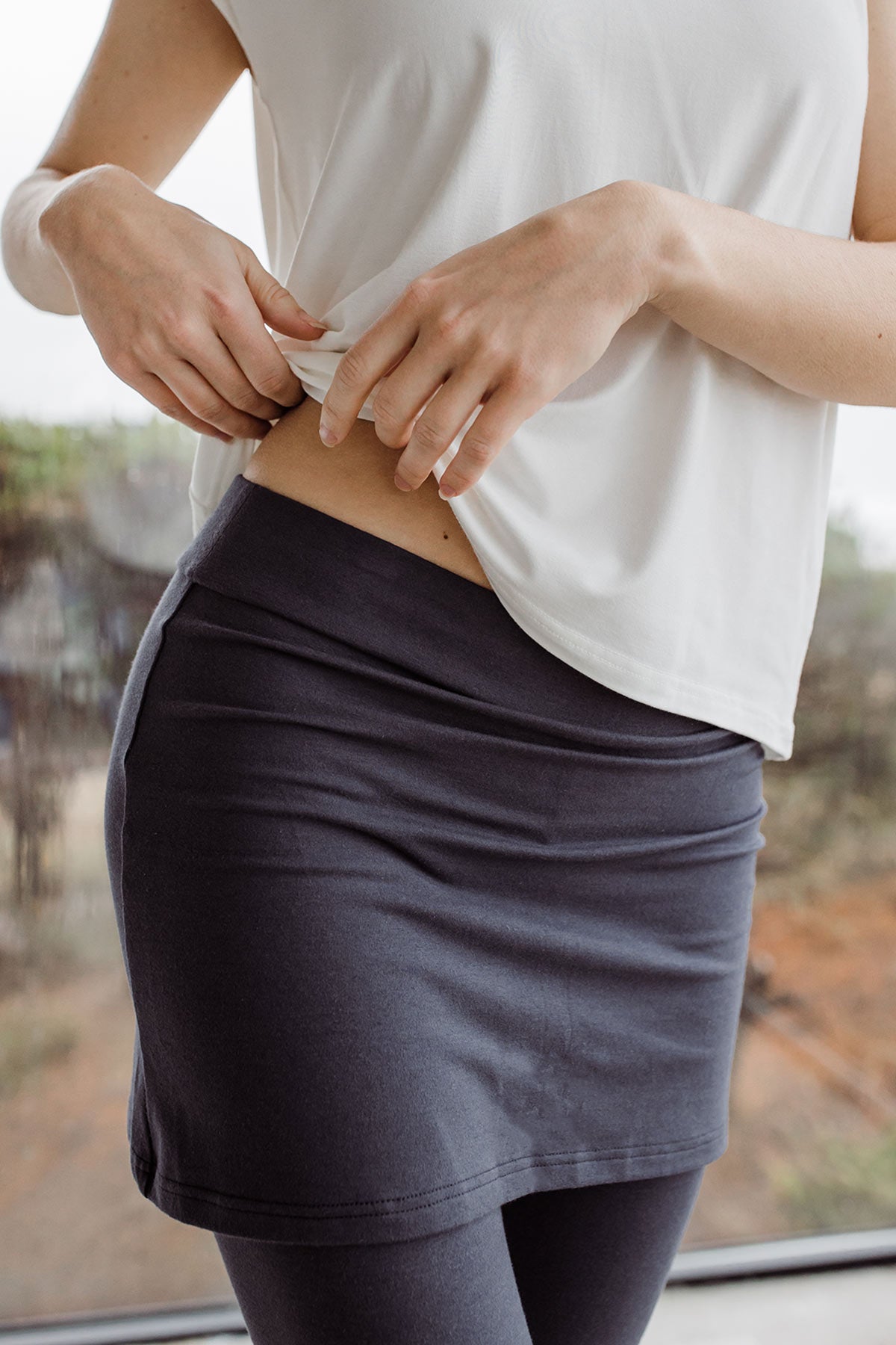 Close-up on woman's waith and hips, wearing Yala Taylor Ultra-Stretch Bamboo & Organic Cotton Skirt Leggings in Hematite