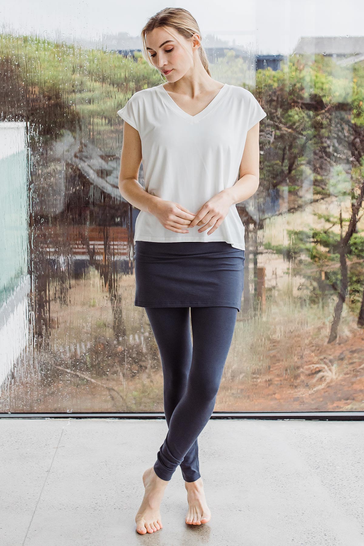 Woman standing and looking downwards, wearing Yala Taylor Ultra-Stretch Bamboo & Organic Cotton Skirt Leggings in Hematite