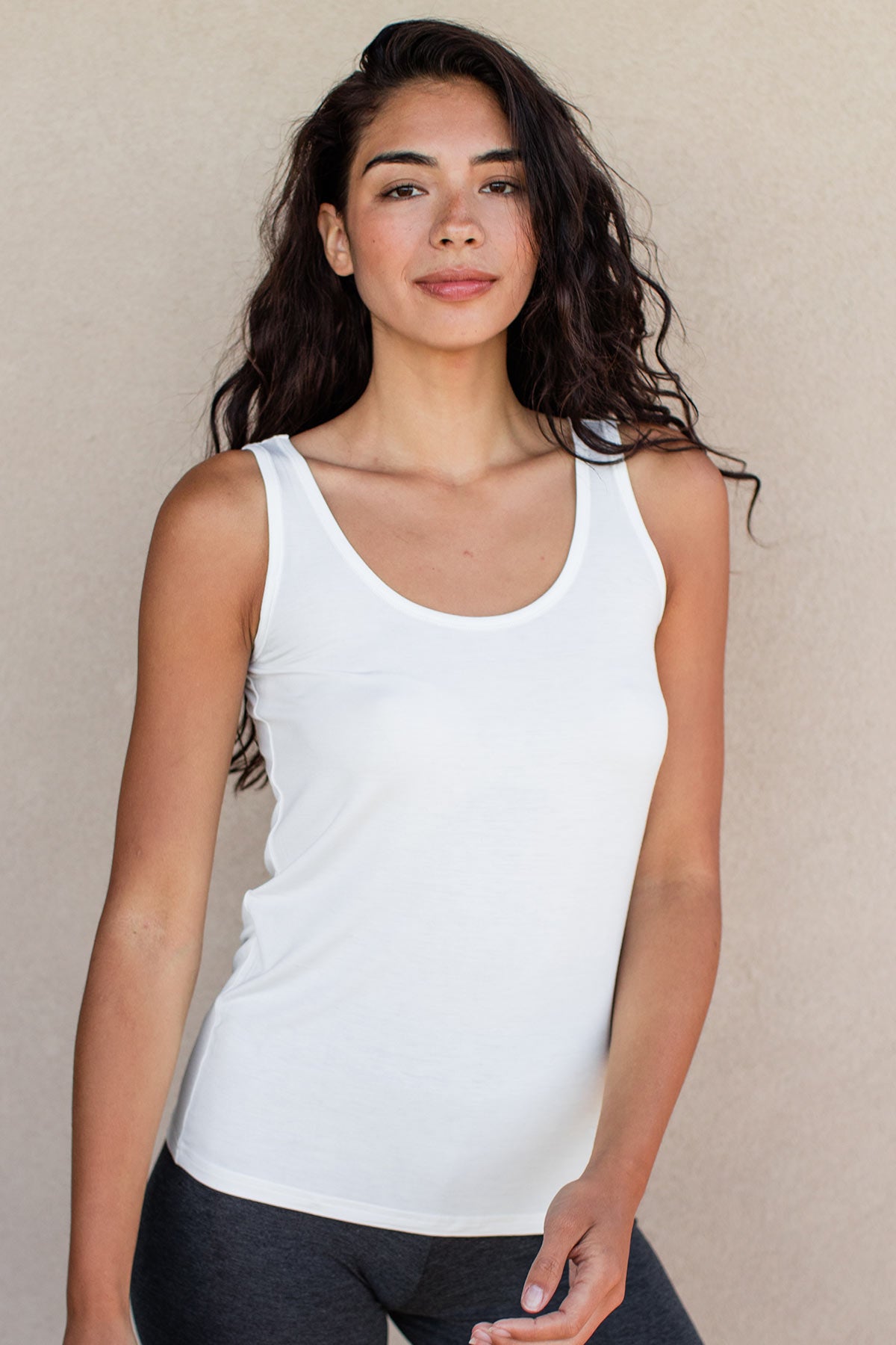 A woman standing with one hand in front of her, wearing Yala Zia Layering Bamboo Tank Top in Natural