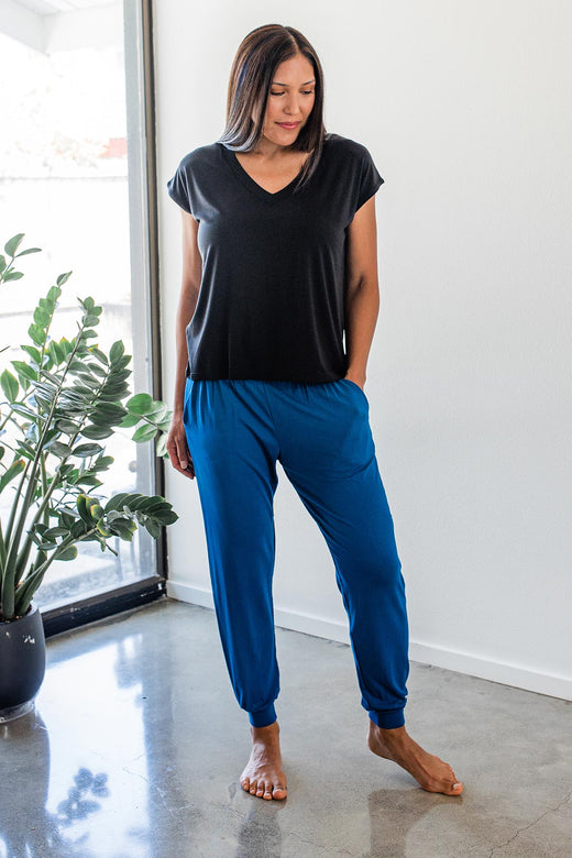 A womand standing with one leg extended and a hand in her pocket, wearing Yala Geena Lightweight Bamboo Jogger Lounge Pants in Lapis