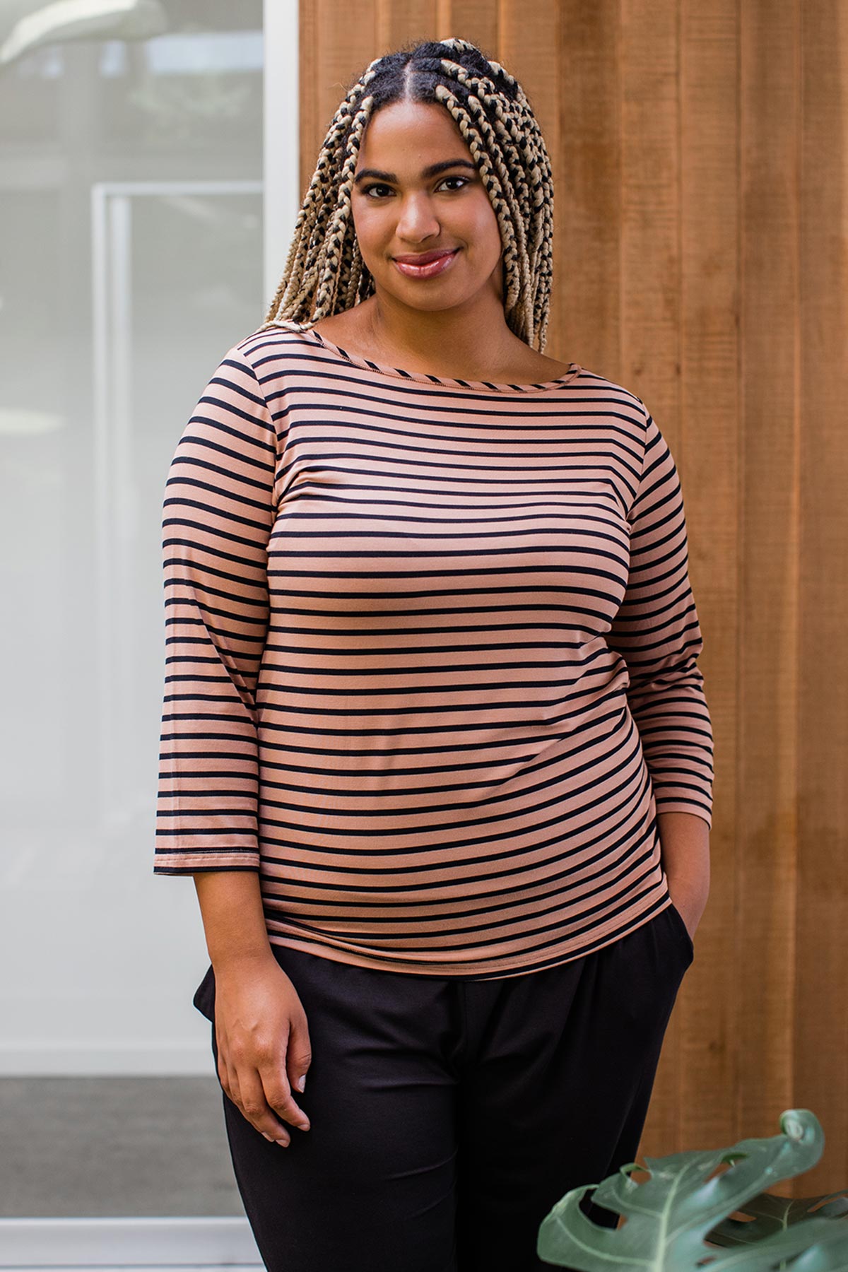 A woman standing with one hand in her pocket and smiling, wearing Yala Kai Boatneck Three Quarter Sleeve Relaxed Fit Bamboo Tee Shirt in Black Newport Stripe