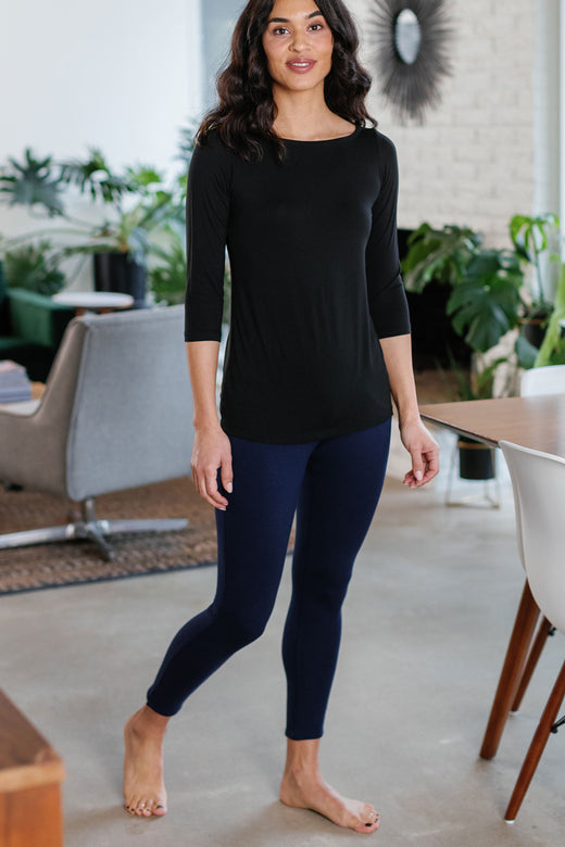 A woman standing with one leg tilted to the side, wearing Yala Abby Mid-Waist Bamboo and Organic Cotton Pencil Pants in Navy