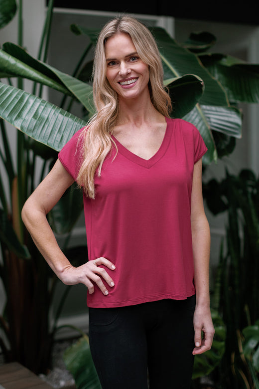 A womand standing and smiling with one hand resting on her hip, wearing Yala Dakota V-Neck Cap Sleeve Bamboo Top in Rosewood