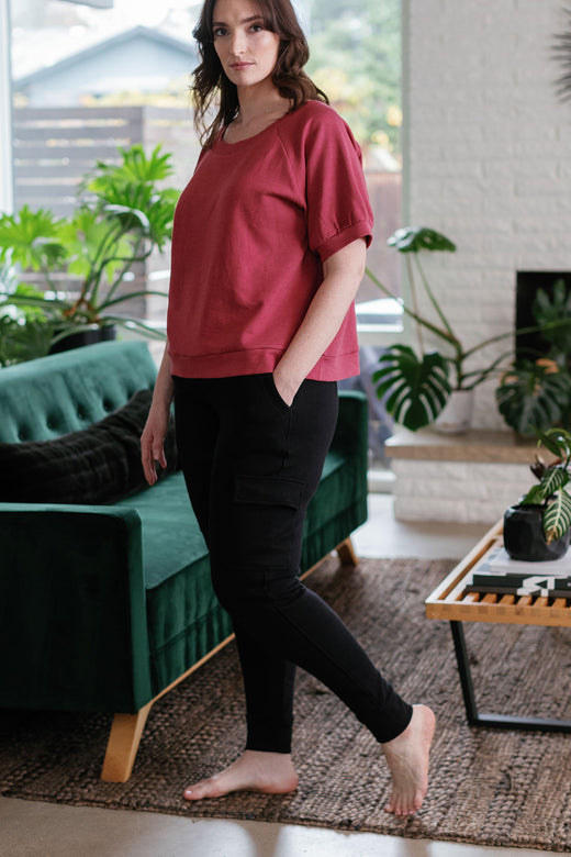 A woman standing to the side, looking towards the camera with one hand in her pocket, wearing Yala Fay Bamboo and Organic Cotton Cargo Joggers in Black