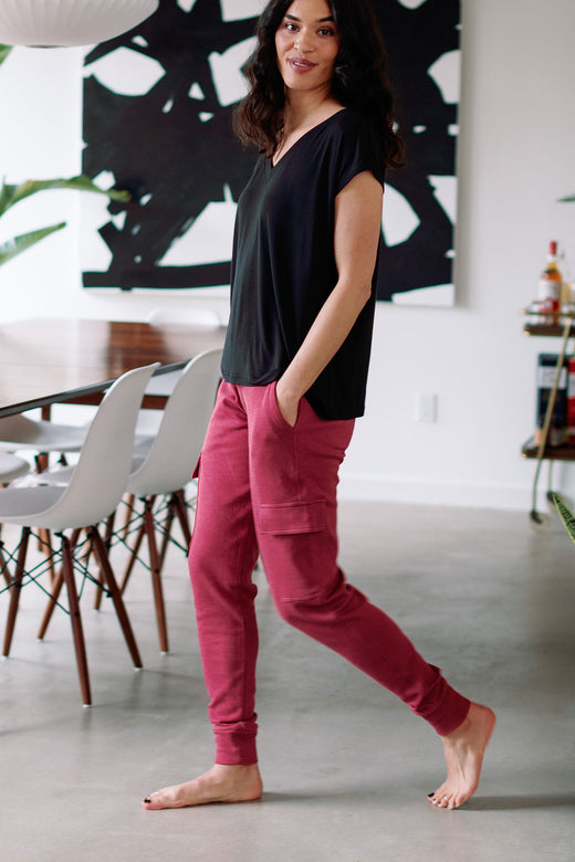 A woman walking to the side and looking at the camer with both hands in her pockets, wearing Yala Fay Bamboo and Organic Cotton Joggers in Rosewood