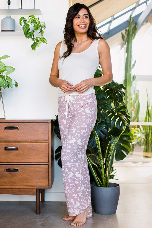 A woman standing and smiling with her hips turned to the side, wearing Yala Gillian Piped Bamboo Pajama Pants in Secret Garden