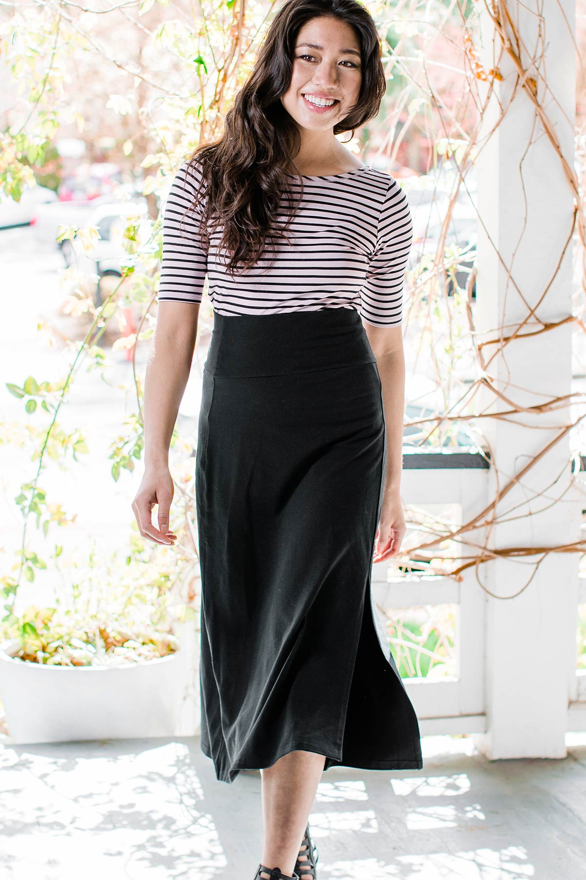 A woman walking forward and smiling, wearing Yala Hannah Ultra-Stretch High-Waisted Bamboo Midi Skirt in Black