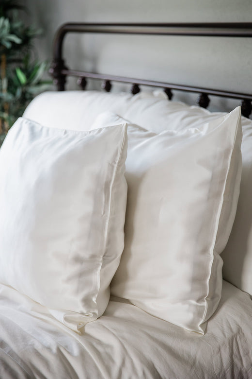 A pair of pillows enshrouded in Yala Charmeuse Pillowcase Set in Natural White