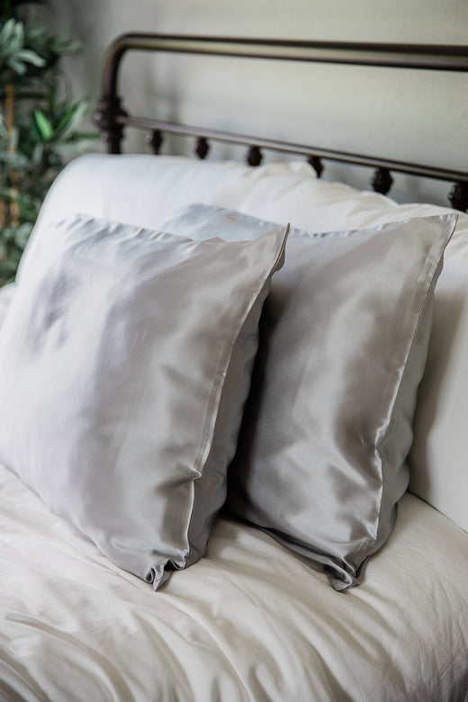 A pair of pillows enshrouded in Yala Charmeuse Pillowcase Set in Pebble Grey